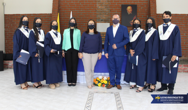 Estudiantes sentados  con toga en la ceremonia con su diploma