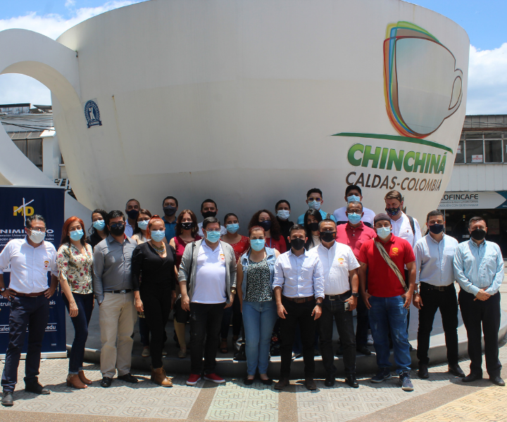 Integrantes de las delegaciones de uniminuto y CINOC junto a la taza de café más grande del mundo, ubicada en el parque de chinchiná.