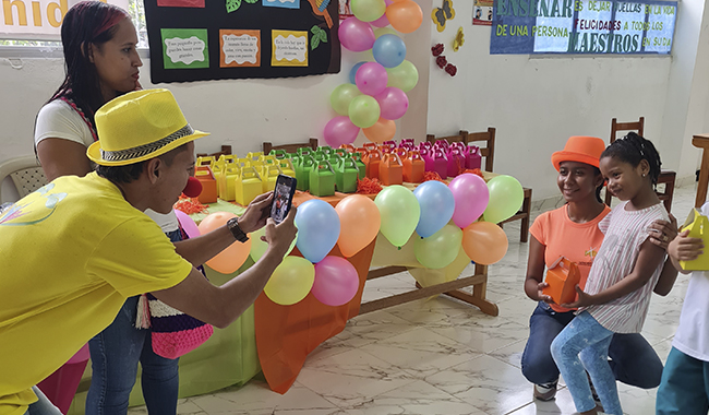 Docente tomándole fotografías a niños participantes de la feria lúdico pedagógica de UNIMINUTO en Urabá