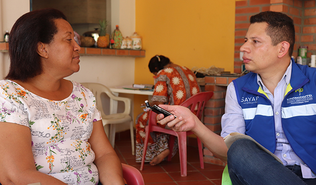 Colaborador de UNIMINUTO dialogando con persona migrante. 