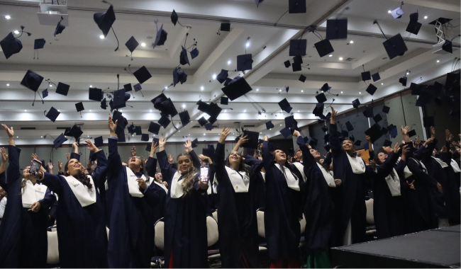 Estudiantes graduandos lanzando birretes al aire