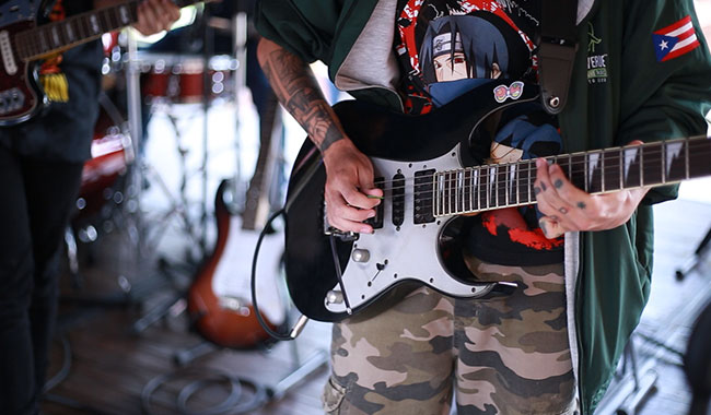 Estudiante de una de las instituciones de educación superior invitadas tocando la guitarra.