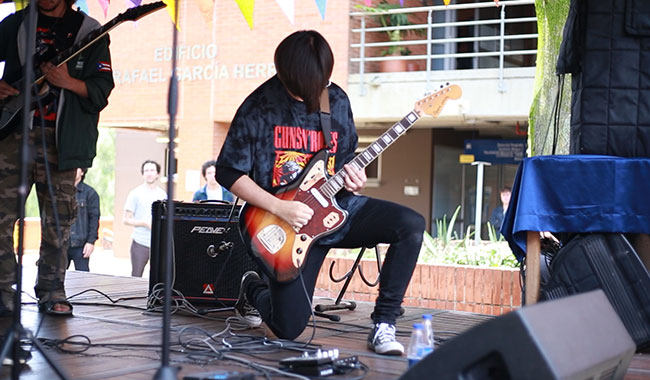 Estudiante de una de las instituciones de educación superior invitadas tocando la guitarra.