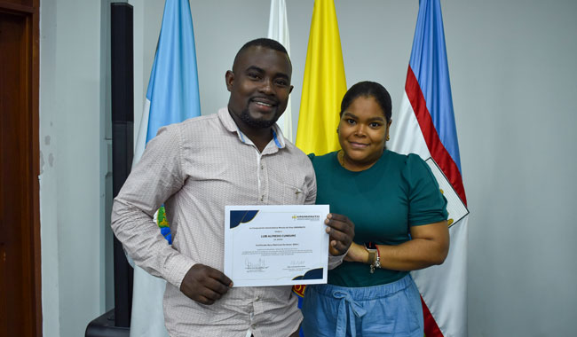 Docente del programa de Tecnología en Informática UNIMINUTO Cali haciendo entrega de reconocimiento a estudiante del programa