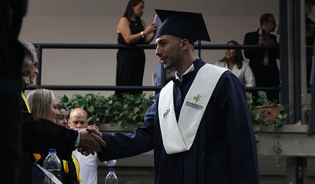 Graduando saludando integrantes de la mesa principal. 