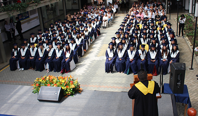 Graduandos con toga y birrete en ceremonia de graduación de UNIMINUTO seccional Antioquia - Chocó.