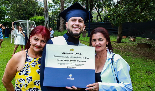 Estudiante graduado sosteniendo su diploma junto a su familia