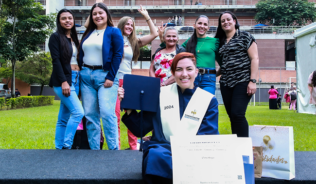 Estudiante graduado sosteniendo su diploma junto a sus familiares