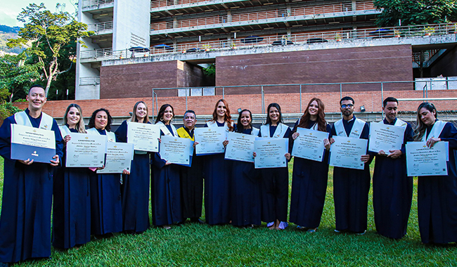 Estudiantes sosteniendo sus diplomas y posando junto al rector de UNIMINUTO