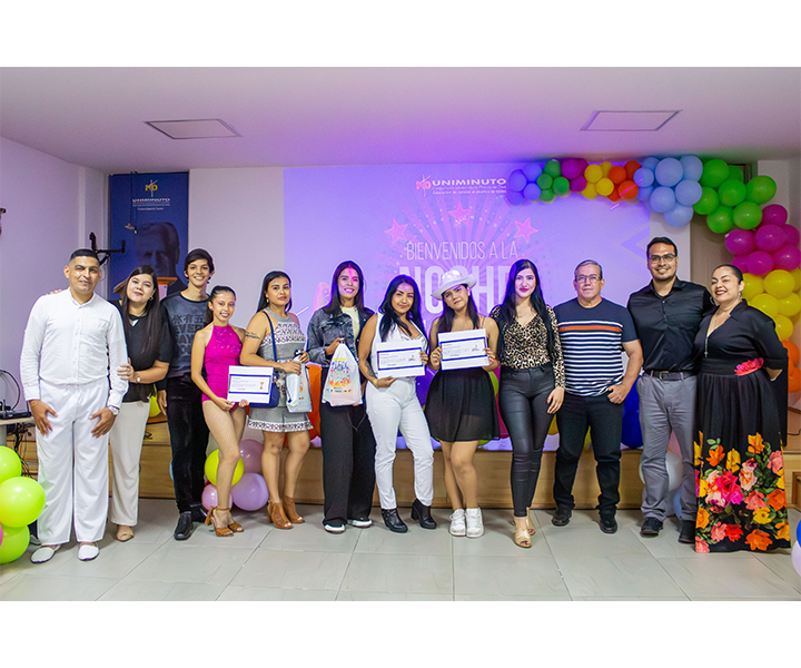 Imagen grupal de los participantes y jurado de la Noche de Talentos en el Centro Universitario Cúcuta, realizada durante la Semana UNIMINUTO 2024. Se observa a los estudiantes que participaron en las categorías de canto y baile, junto con los miembros del jurado. El evento estuvo decorado con globos de colores, creando un ambiente festivo y alegre.