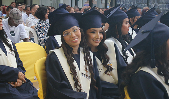 Dos estudiantes con toga y birrete en la ceremonia de certificación de UNIMINUTO