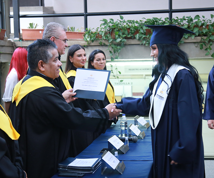 Estudiante con toga y birrete recibiendo el certificado entregado por el rector de UNIMINUTO seccional Antioquia - Chocó