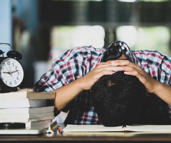 Estudiante recostado en su escritorio con un notorio caso de estrés.