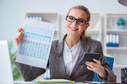 Mujer sentada en escritorio con documento y calculadora en la mano