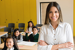 Profesora en salón con niños sentados en pupitres