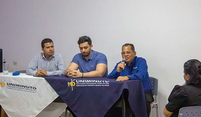 Mesa principal del IX Coloquio de Posgrados con José Albeiro Tamara, Brian Bustos y José Alberto Cristancho, quien se dirige al público con un micrófono