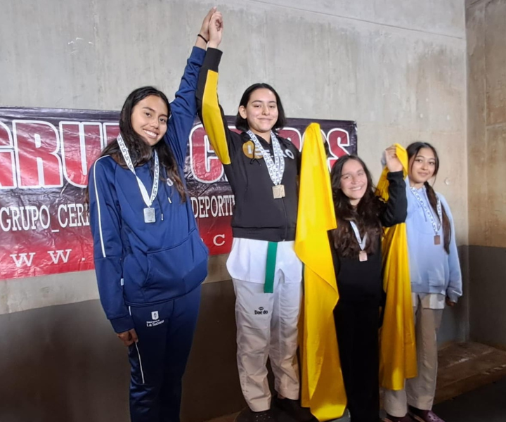 Estudiantes en podio posando con medalla de reconocimiento