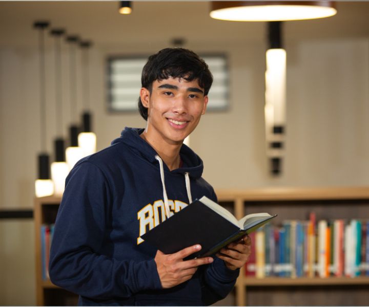 estudiante con un libro en una biblioteca