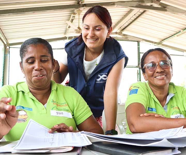 Dos mujeres con el tallerista trabajando en la generación de su plan de mercadeo