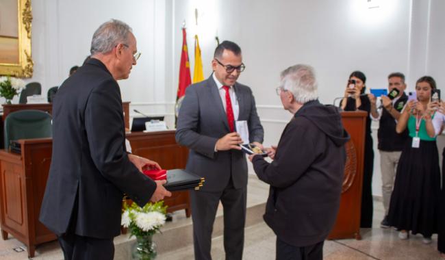 El Gobernador encargado de Norte de Santander entrega una condecoración al Padre Diego Jaramillo durante una ceremonia oficial en la Asamblea Departamental