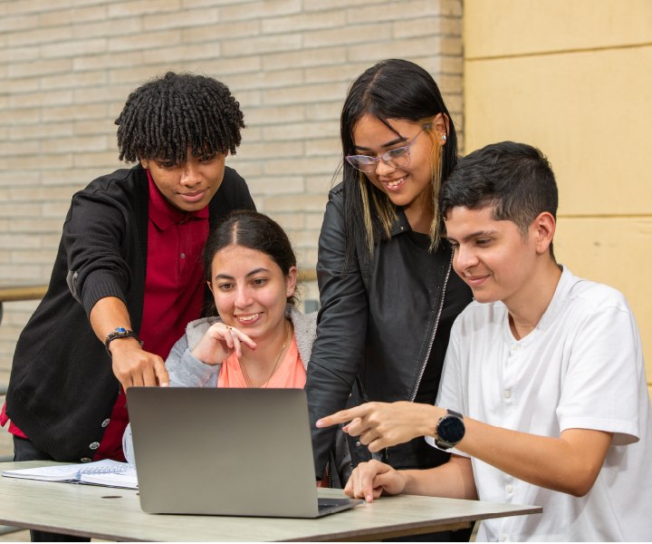 Estudiantes en campus universitario viendo computador