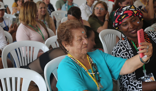 Mujer adulta mayor, sentada sosteniendo un teléfono móvil