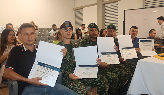 Grupo de participantes, incluidos miembros del Ejército Nacional, sostienen sus certificados durante la ceremonia del curso de drones en aula.