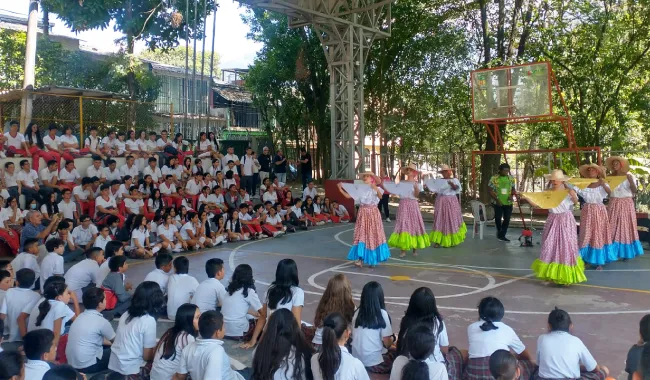 Grupo cultural de UNIMINUTO en frente de estudiantes de colegio
