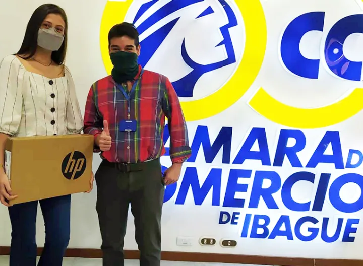 Mujer sosteniendo un premio (computador portatil), al lado hay un hombre 