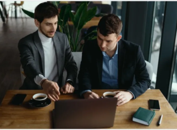Dos personas trabajando frente a un computador portatil