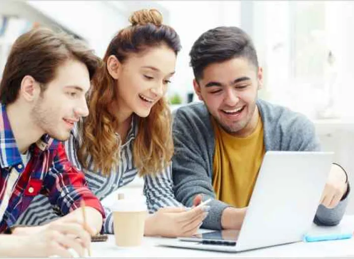Dos estudiantes hombre y una mujer frente a computador portatil estudiando