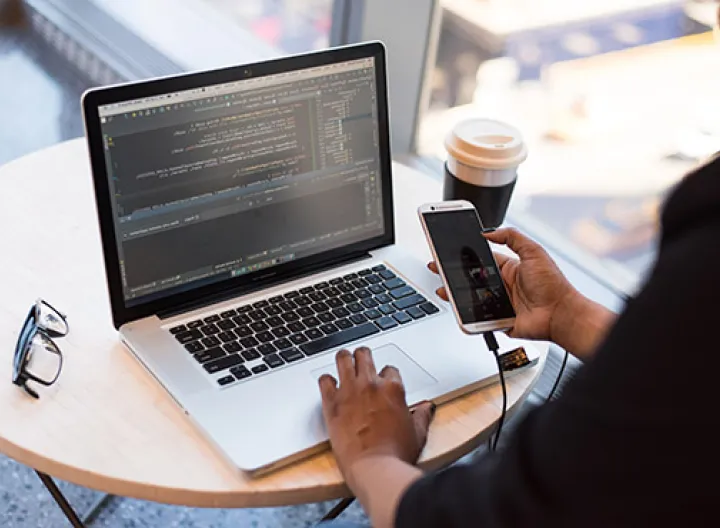Persona trabajando en su escritorio con un computador y un celular