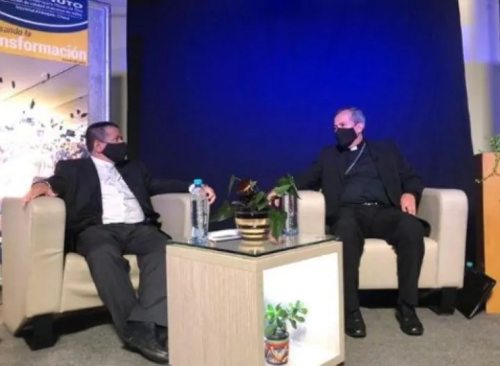 Dos personas sentadas en sofá y con distanciamiento, en diálogo academico (Rector UNIMINUTO Bello y Arzobispo de Medellín) 