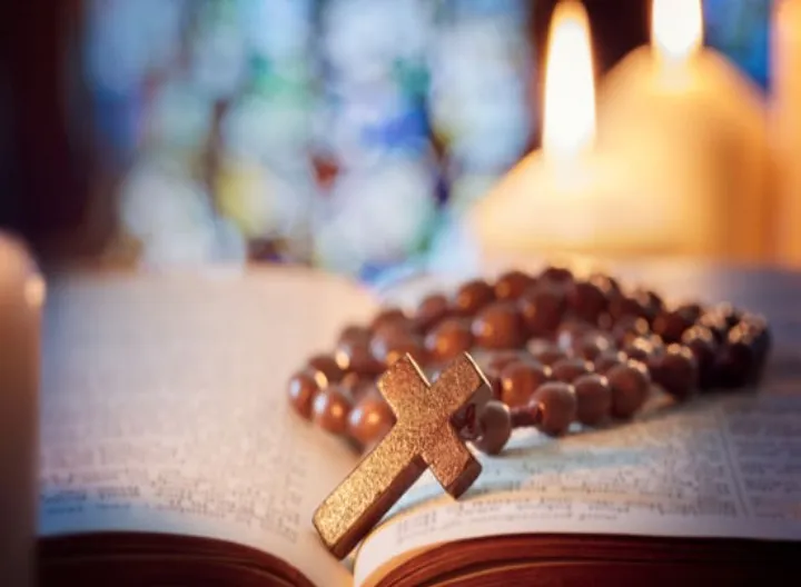 Biblia abierta y camándula en medio