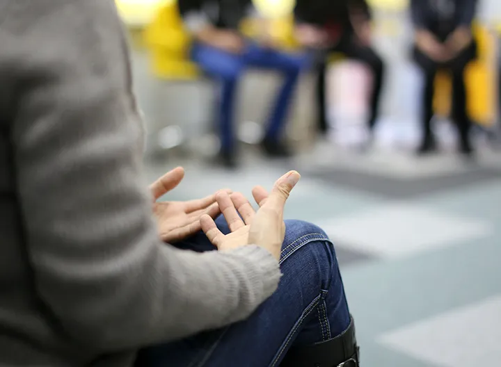 Mujer sentada liderando conversación al estilo mesa redonda 