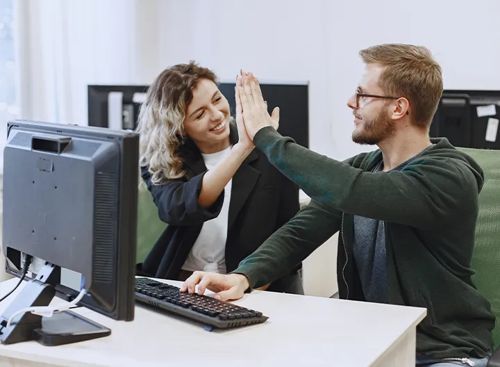 Estudiantes chocando las manos frente al computador