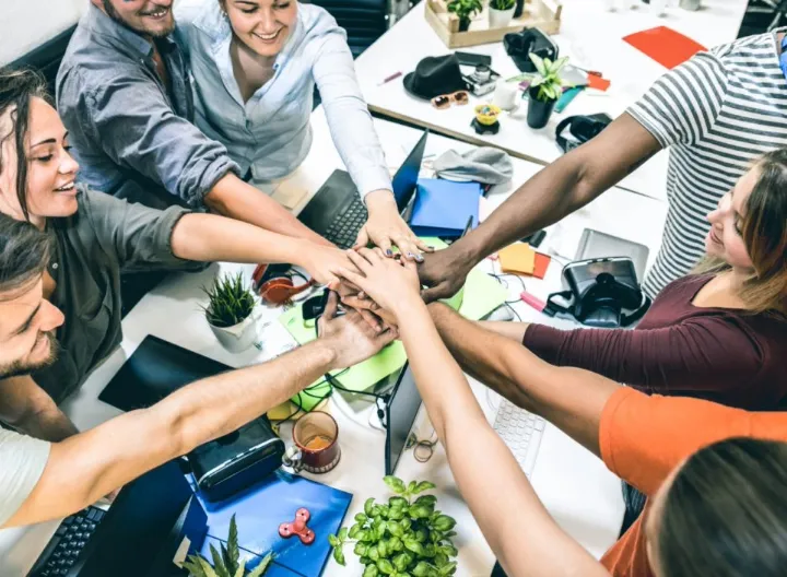 Nueve emprendedores juntando sus manos en señal de unión. 