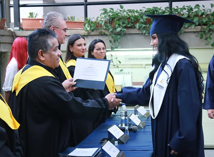Estudiante con toga y birrete recibiendo el certificado entregado por el rector de UNIMINUTO seccional Antioquia - Chocó