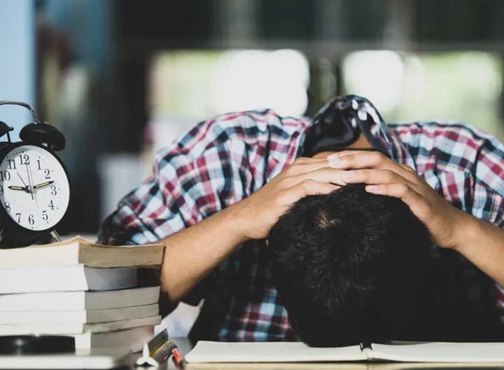 Estudiante recostado en su escritorio con un notorio caso de estrés.