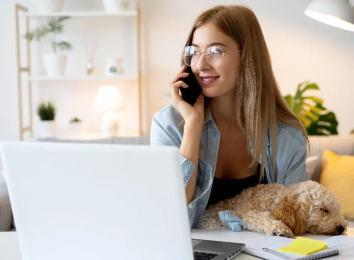 mujer hablando por celular acompañada de su mascota