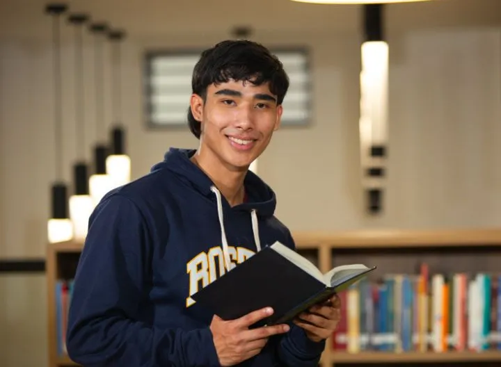estudiante con un libro en una biblioteca