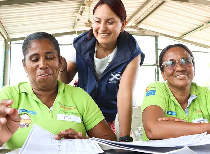 Dos mujeres con el tallerista trabajando en la generación de su plan de mercadeo