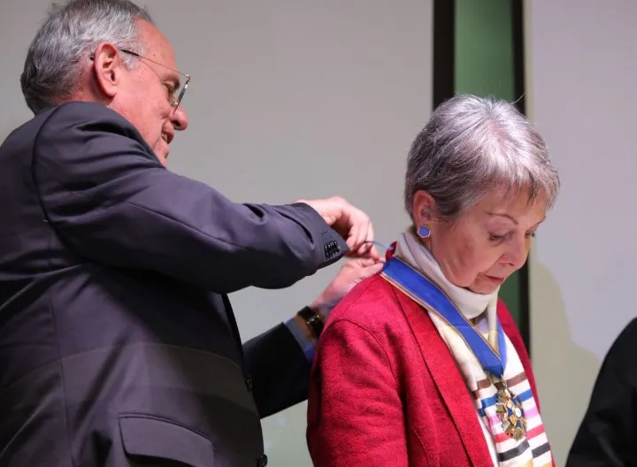 Foto del padre Camilo Bernal entregando la condecoración a la doctora Sara Ordóñez Noriega