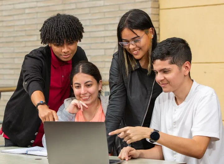 Estudiantes en campus universitario viendo computador