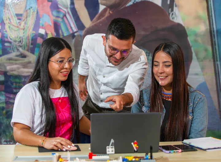Estudiantes sonrientes viendo computador
