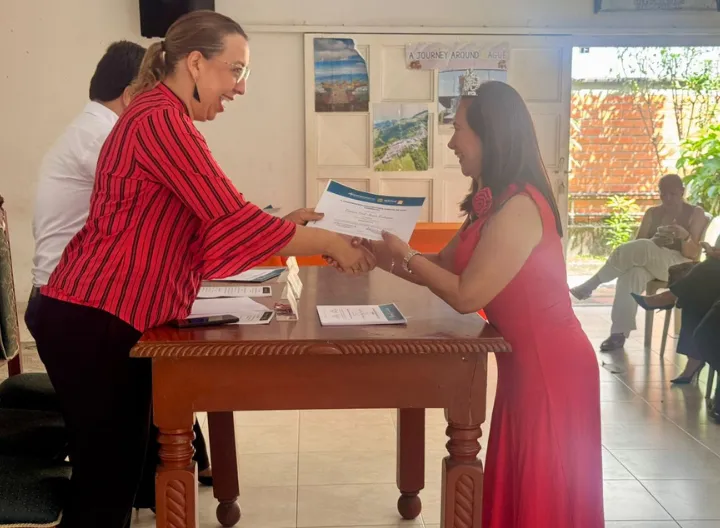 Rectora de UNIMINUTO Tolima–Huila entregando microcredencial en inglés a docente durante acto de certificación en Ibagué, como parte de la estrategia de fortalecimiento del bilingüismo educativo.