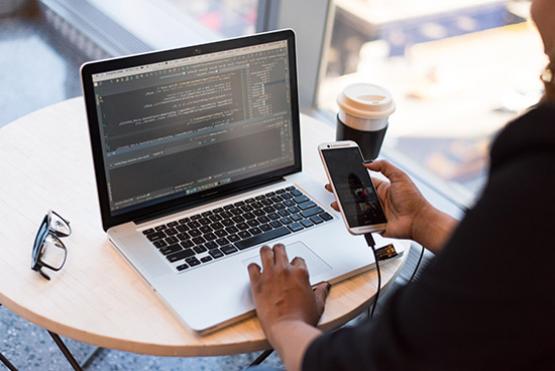 Persona trabajando en su escritorio con un computador y un celular