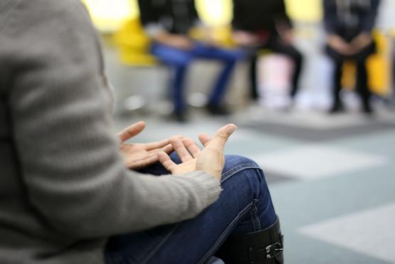 Mujer sentada liderando conversación al estilo mesa redonda 