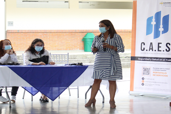 En la plazoleta del campus en Pereira, en una mesa de mantel blanco, los asistentes atienden a la presentación de los servicios del CAES en Pereira