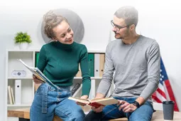 mujer con unas hojas y un hombre con un libro